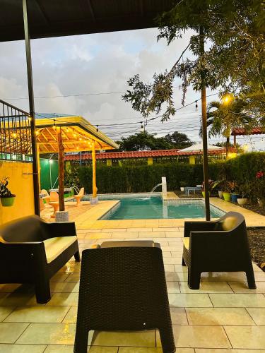 a swimming pool with two chairs and a table at Hotel La Fiore de Bahia in Uvita