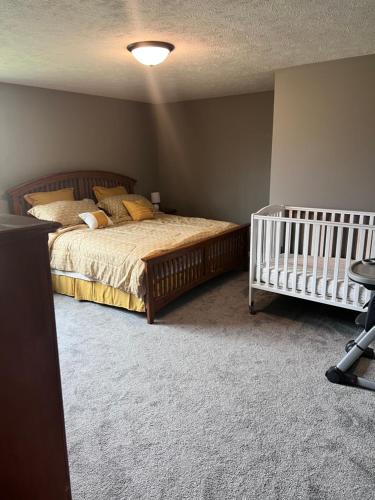 a bedroom with a bed and a crib in it at Petit Domicile Rare Deluxe Family King with Shared Bathroom in Lincoln