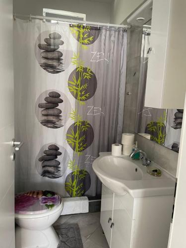 a bathroom with a shower curtain with a toilet and a sink at Apartments Green Oasis in Vlašići