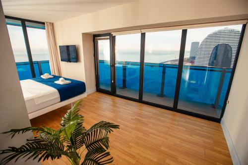 Habitación con cama y ventanas grandes de cristal. en Panorama Batumi Beach Resort en Batumi