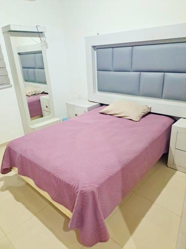 a bedroom with a purple bed and a mirror at Departamento Moderno Alberca Compartida - 6 Personas in Mazatlán