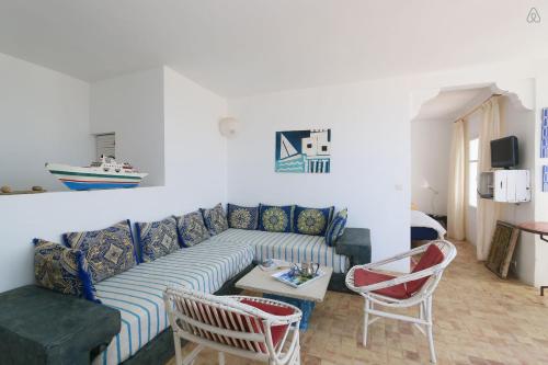 a living room with a couch and a table and chairs at Villa vue mer Mirleft - ménage et Cuisinière à mi-temps in Mirleft