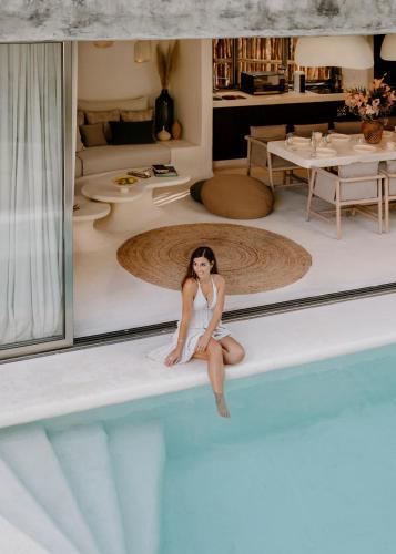 a woman sitting on the edge of a swimming pool at Hotel Milam in Tulum