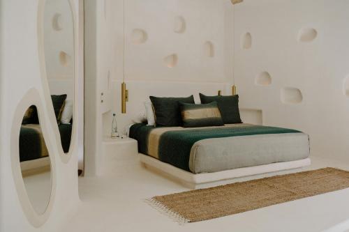 a white bedroom with a bed and a mirror at Hotel Milam in Tulum