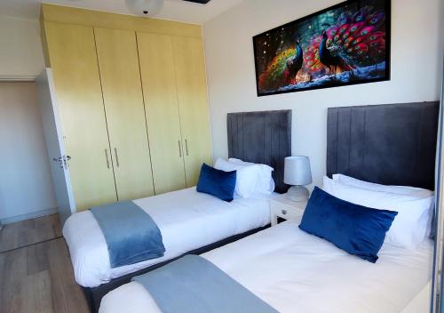 two beds with blue pillows in a room at Cape Town Luxury Stays Knightsbridge Luxury Apartment Century City in Cape Town