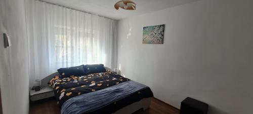Schlafzimmer mit einem Bett mit blauer Bettwäsche und einem Fenster in der Unterkunft La Bloc Apartment in Arad