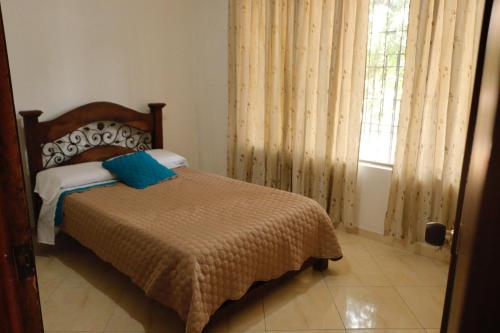 a bedroom with a bed and a window with curtains at Genesis Hospedaje Yopal in Yopal