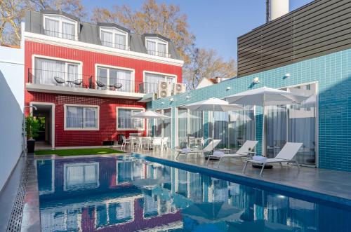 蒙蒂茹的住宿－2M BOUTIQUE HOTEL，一座带椅子和遮阳伞的游泳池位于一座建筑旁边