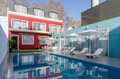 a pool with chairs and umbrellas next to a building at 2M BOUTIQUE HOTEL in Montijo