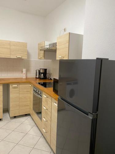 uma cozinha com um frigorífico preto e armários de madeira em Wohnung gegenüber vom Theater em Gera