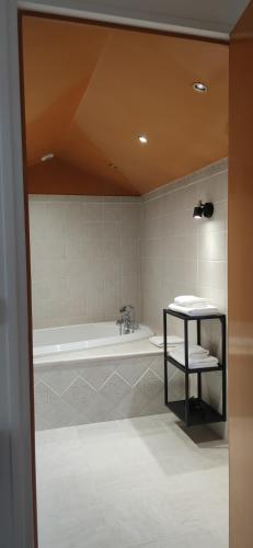 La salle de bains est pourvue d'une baignoire, d'une table et d'un lavabo. dans l'établissement Au Lampadaire Briarois, à Briare