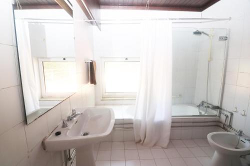 een witte badkamer met een wastafel en een bad bij Casa dos Filhos - Casas do Rio by Gerês Casas in Vieira do Minho