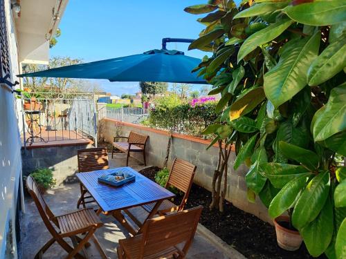 a patio with a table and chairs and a blue umbrella at A casa di Gina in Rosignano Solvay