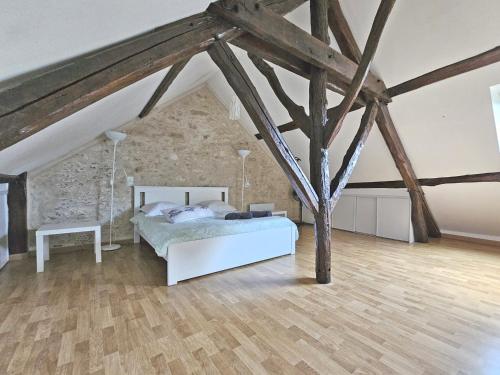 um quarto com uma cama branca e piso em madeira em Triplex Sisley - Maison Atypique avec Cour Extérieure em Moret-sur-Loing