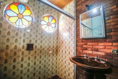 uma casa de banho com um lavatório e vitrais. em Suítes para locação próximo ao Capivari em Campos de Jordão