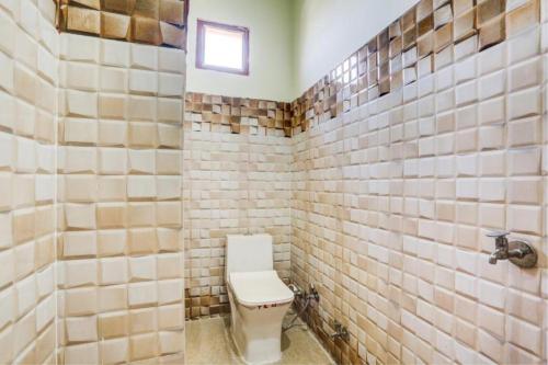 a bathroom with a toilet and tiled walls at Goroomgo Hotel M J Agra Near Taj Mahal 950m in Agra
