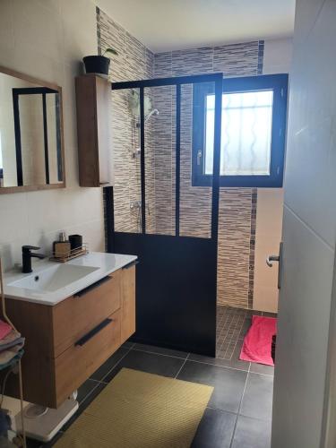 une salle de bain avec un lavabo et une douche avec une fenêtre dans l'établissement Les Alizés, à La Bâtie-Rolland