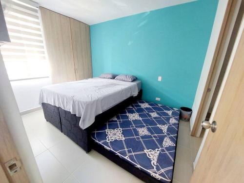 a bedroom with a bed and a blue wall at Acogedor Apartamento en Ricaurte, Cundinamarca in Girardot