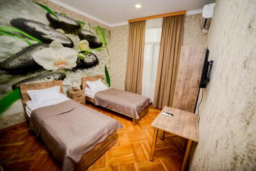 a room with two beds and a wall with a painting at Hotel Samta in Tskaltubo