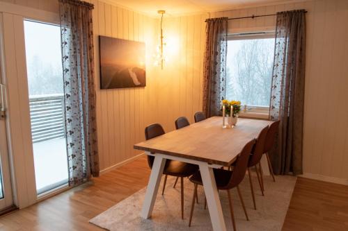 een eetkamer met een houten tafel en stoelen bij Senja, 2 BR apartment, surrounded by the northern lights and the midnight sun in Finnsnes