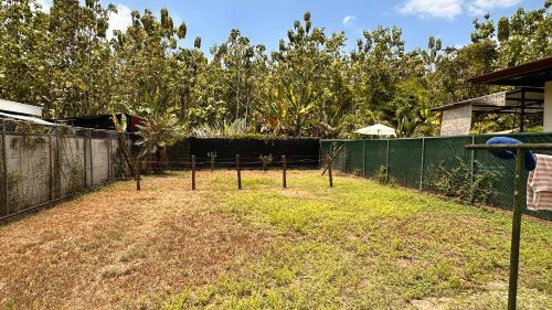 een tuin met een hek met bomen erin bij Habitación Cerca de las playas y Golfito in Palmar Norte