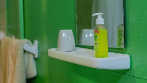 a green bathroom with a bottle of mouthwash on a sink at L'Address in Cotonou