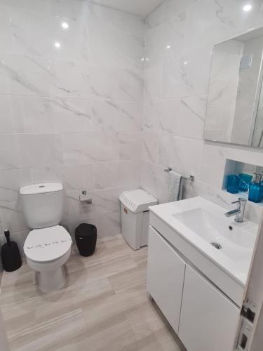 a white bathroom with a toilet and a sink at venha nadar a oura in Albufeira
