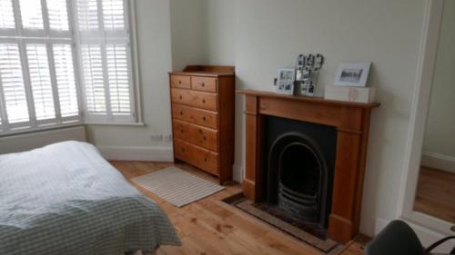 a bedroom with a fireplace and a dresser and a bed at London 2 Bed Flat Zone2 in London