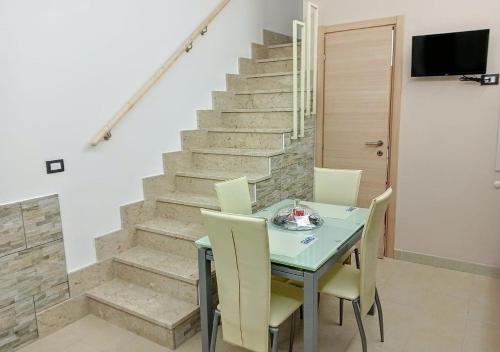 uma sala de jantar com mesa, cadeiras e escadas em sciuliddA Casa Vacanze em Avola