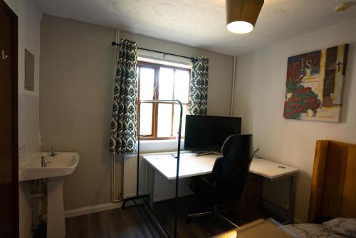 a room with a desk with a computer and a sink at Sevenoaks Guest House in Trimley Heath