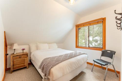 a bedroom with a bed and a chair and a window at Indigo Owl by AvantStay Cabin w Hot Tub Firepit Minutes to Lake Slopes in Homewood