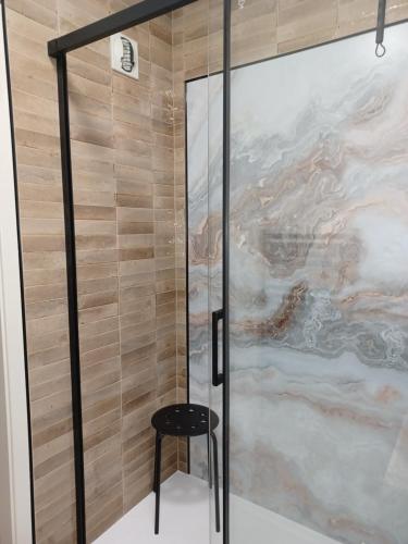 a shower with a stool next to a glass door at Le Nid Cosy Obernai, Terrasse, Garage, 3 étoiles hébergement de très bon confort in Obernai