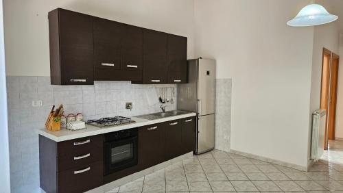cocina con armarios marrones y nevera de acero inoxidable en Compatri House, en Osteria dellʼ Osa