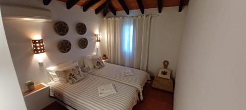 1 dormitorio con 1 cama con sábanas blancas y ventana en Cozy Beach House, en Santa Luzia