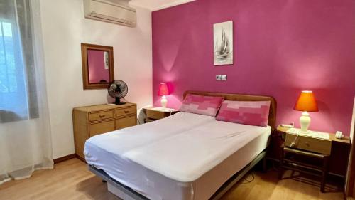 1 dormitorio con cama y pared de color rosa en El Cortijo PB 7, en L'Estartit