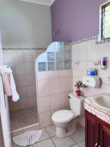 a bathroom with a toilet and a shower and a sink at Hotel La Fiore de Bahia in Uvita