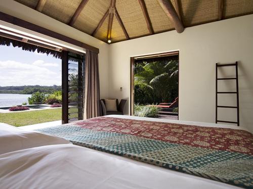 a bedroom with a large bed and a large window at Eratap Beach Resort in Port Vila