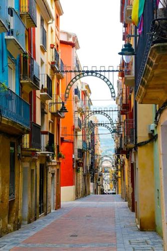 an alley between buildings with an arch in the distance at Ático con vistas a la montaña Alcoy in Alcoy