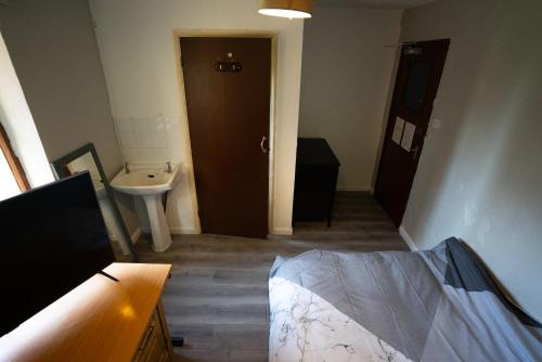 Zimmer mit einem Bad mit einem Waschbecken und einer Tür in der Unterkunft Sevenoaks Guest House in Trimley Heath