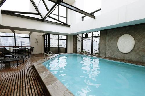 a large swimming pool in a building with windows at Apart-hotel 1804 - Le Premier Suítes Jardim Paulista in Sao Paulo