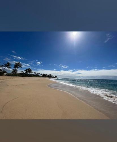 a beach with palm trees and the ocean on a sunny day at New 4 Bedroom Home with Ocean and Gorgeous Mountain Views in the gated community of Mauna Olu in Waianae