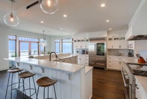 una cocina con armarios blancos y una gran isla con taburetes. en La Jolla Cove-Oceanfront 5600SF 3BR+Loft 5BA House best Villiage location walk everywhere, en San Diego
