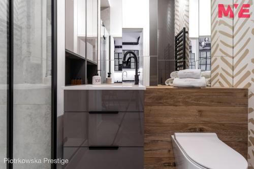a bathroom with a sink and a toilet and a mirror at MYE Apartments - Piotrkowska 44 in Łódź