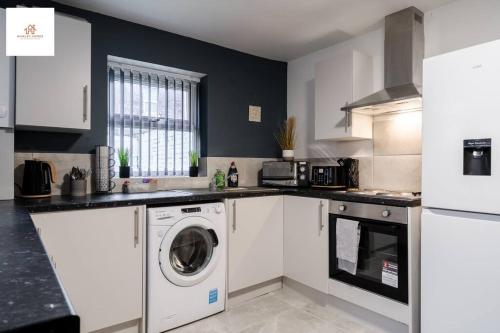 cocina con armarios blancos, lavadora y secadora en Large 3 bedroom sleeps-7/Gartson/Liverpool, en Liverpool