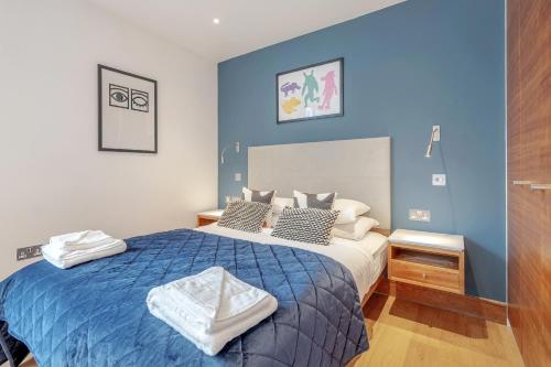 a bedroom with a bed with a blue wall at Stay Kula London - Tower Hill in London