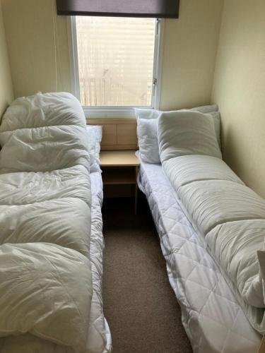 two beds sitting in a room with a window at B&T caravans in Ingoldmells