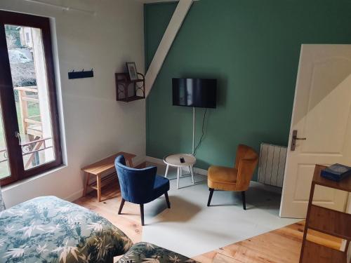 a bedroom with a bed and chairs and a tv on the wall at Chambres d'Hôtes du Domaine de Bourbacoup in Tulle