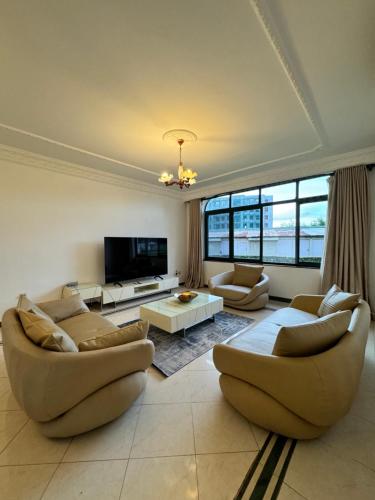 a living room with two couches and a tv at Hello sunshine in Dar es Salaam