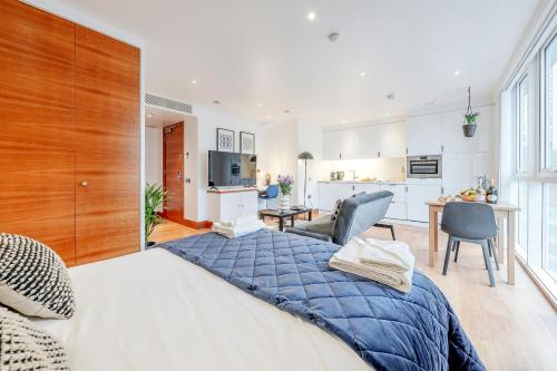 a bedroom with a large bed and a kitchen at Stay Kula London - Tower Hill in London