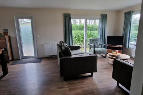 a living room with a couch and a chair at Mooi chalet op prachtige plek in het groen in Voorthuizen